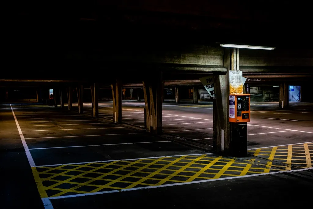 Empty multi-story parking garage at night, warm pay-here kiosk in view